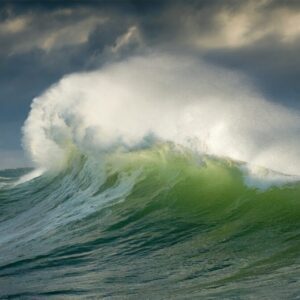 Dramatic Green Ocean Wave Crashing Under Stormy Grey Sky